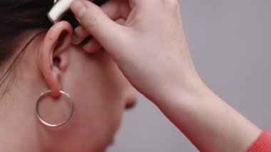 Kadın işitme cihazı takıyor. İşitme kaybı belirtileri gösteren yaşlı bir kadın. Olgun dişinin parmakları kulağına yakın. İşitme cihazı olan kadın.