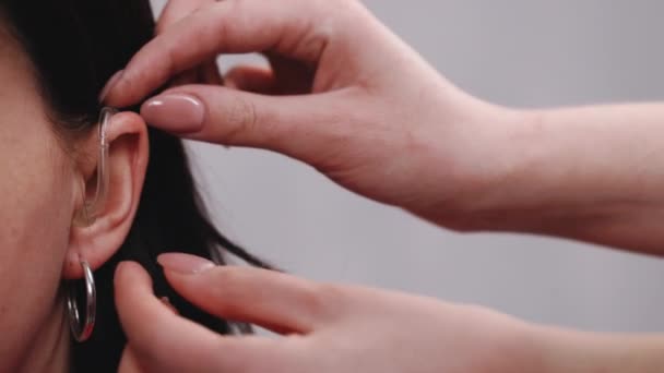 Happy woman takes off her hearing aid. Woman with symptom of hearing loss. Female nurse takes off a hearing aid. Hearing aid concept — Stock Video