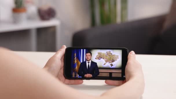 Kyiv, Ukraine April 7 2022: Woman watches the speech of the president of Ukraine Volodymyr Zelensky on smartphone. News about tensions between Ukraine and Russia. Russian aggression. Threat of war — Stock Video