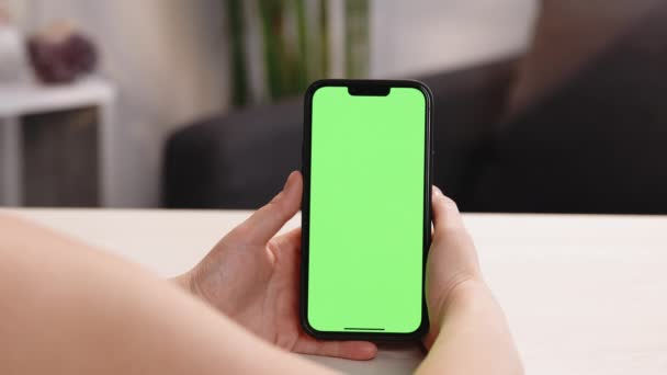 Gebruik groen scherm voor kopieerruimte close-up. Chroma key mock-up op de smartphone in de hand. Vrouw houdt mobiele telefoon binnen van gezellige huis — Stockvideo