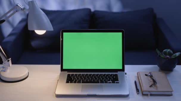 リビングルームのテーブルの上にクロマキー緑の画面をモックアップと現代のラップトップ。クロマキー技術のための緑の画面を持つノート。自宅で仕事のためのデスクを設定します。4kテンプレートの技術コンセプト — ストック動画