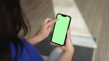 Dikey Kipte Akıllı Telefon Kullanan Kadın Yeşil Model Ekranlı, Kaydırma Hareketleri Yapıyor. Cep telefonu, internet sosyal ağları tarama haberleri, mali raporlar. Görünüm Kamerası Noktası.