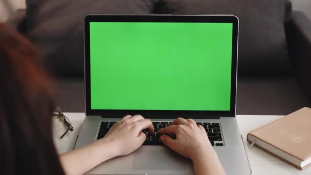 Persona irreconocible Primer plano Shot Woman utiliza el ordenador portátil con pantalla verde simulada mientras está sentado en el escritorio en su acogedora sala de estar — Vídeo de stock