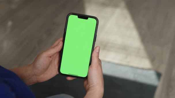 Крупним планом знімок зеленого екрану шаблону смартфона в жіночих руках вдома. Дівчина дивиться контент, не торкаючись екрана гаджета. Використовувати макет для простору копіювання. Модульна технологія та інформаційна концепція — стокове відео