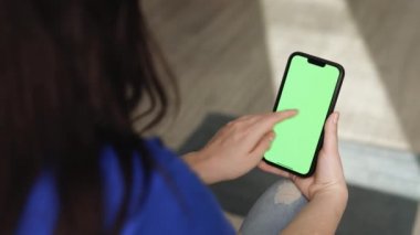 Kadının elinde cep telefonu, akıllı telefon ve kapalı bir evde çekilmiş fotoğraflar ya da fotoğraflar var. Chroma tuşu elinde akıllı telefondan model alınıyor. Kopyalama alanı için yeşil ekran kullan