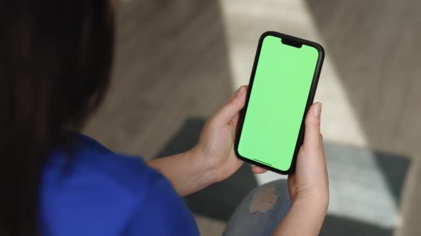 緑の画面のクロマキーの背景にスマートフォンを保持認識できない女性の手。縦向きのポートレートモードで製品の携帯電話のモックアップ。女性の手で空白のデジタルスマートフォン — ストック動画