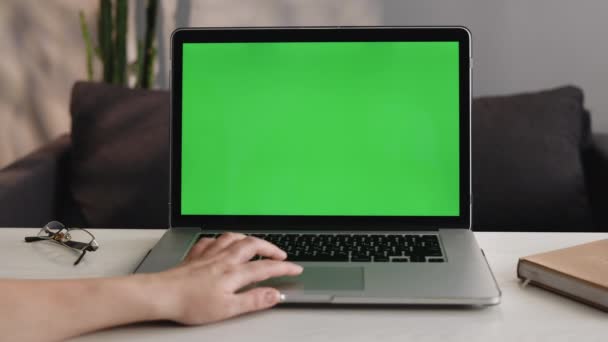 ラップトップコンピュータで緑色の画面のモックを閉じます。デバイスは現代の家庭のテーブルで使用されます。認識できない人はタッチパッドを使用します。健康的なライフスタイルのVibesのある日当たりの良いモダンな部屋 — ストック動画