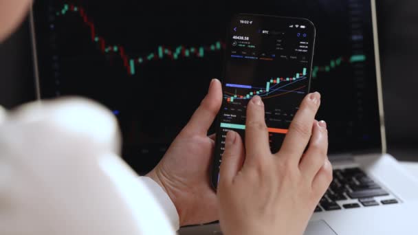 Les investisseurs négocient des valeurs mobilières. Utilisation de smartphones et d'ordinateurs. Gros plan du trader d'actions au bureau avec les données de cours des actions affichées sur l'ordinateur portable et l'application smartphone. Analyse des risques des agents de change — Video