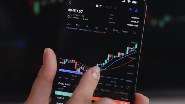 Makler przegląda dane na ekranie. Zbliżenie kobiety sprawdza wykres cen Bitcoin na cyfrowej wymiany na smartfonie, kryptowaluta przyszłych przewidywań cen akcji. Analityk finansowy. — Wideo stockowe