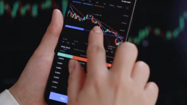 Yakından, geceleri dizüstü bilgisayarın önünde kayan bir kadın. Kodlayıcı, akıllı telefondan dijital değiş tokuş üzerinde Bitcoin fiyat grafiğini kontrol ediyor, kripto para birimi gelecek fiyat öngörüsü.