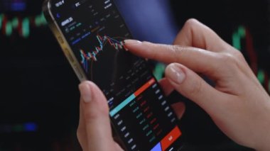 Kadının yakınlaşması, akıllı telefon, kripto para birimi gelecekteki fiyat öngörüsünde Bitcoin fiyat tablosunu kontrol ediyor. Borsacı ekrandaki verilere bakıyor. Finansal analist.