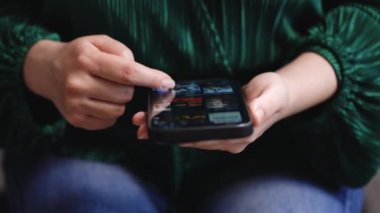 Finger of woman touching scroll page app on mobile phone smartphone. Browsing movie video in the internet library to watch film online