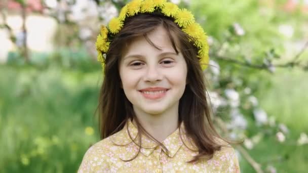 Portrait of happy smile girl with a wreath on her head in summer. Girl face in park close-up. Happy face of a child. Child smiles at camera. Face close-up. Happy child in park. Beautiful face. — стоковое видео