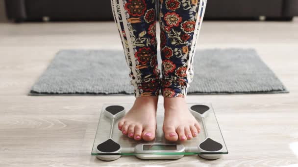 Närbild av barfota kvinna med hjälp av digitala skalor och kontrollera hennes vikt. Kvinnliga fötter kliver på våningsvågen. Begreppet kost, gå ner i vikt och hälsosam livsstil — Stockvideo