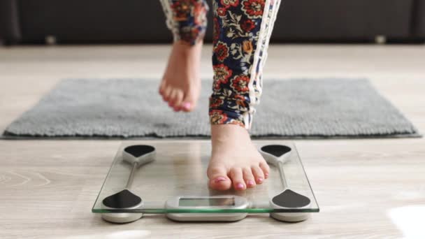 Close-up of slender woman bare legs take step on scale. The female checks his weight after training at home. Woman registers weight and fat percentage on digital weight, healthy lifestyle — Video Stock