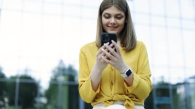 Akıllı telefon mesajlarında sosyal medya uygulaması kullanarak genç, zarif, beyaz bir kadının ilgisini çekmek açık havada gülümseyen haberler alıyor. Halk portreleri ve teknoloji konsepti.