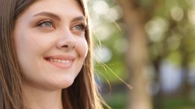 Gün batımında çekici esmer bir kadın mavi gözlerin etrafında gülümsüyor. Dışarıda dur ve rahatla. Mutlu rahatlama. Kapatın. Yavaş çekim