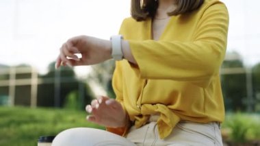 Beyaz bir kadın şehirde akıllı dijital cihaz kullanıyor. Akıllı saat. Akıllı sekte kaydırma ekranı. Akıllı saat uyarısı kontrol ediliyor. Dokunmatik Ekran Giyilebilir Teknoloji Akıllı Grup.