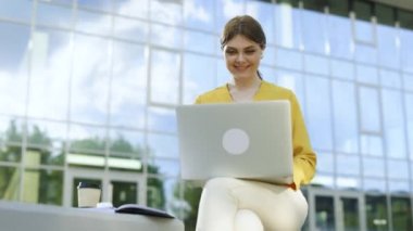 Beyaz iş kadını ofisin dışında dizüstü bilgisayar arıyor. Gülümseyen kız dışarıda defter başında kahve içiyor. Uzak bir iş yerinde dizüstü bilgisayara gülümseyen mutlu iş kadını