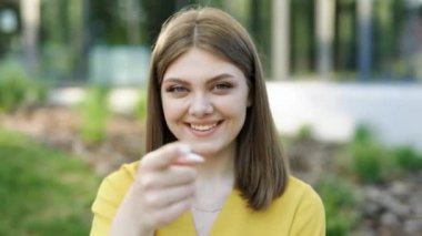 Güzel Avrupalı Ukraynalı kız işaret parmağıyla kamerayı işaret ederek el hareketleriyle davet ediyor. Etnik açıdan mutlu genç bir kadın bir şey göstermek ve vücut dili konuşmak için arıyor. Hey sen, buraya gel..