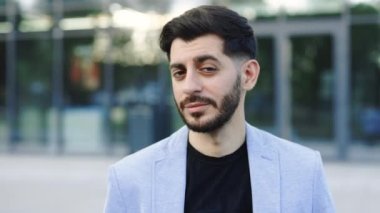 Yakışıklı, pozitif sakallı iş adamı patron yönetici başarılı işverenin yüzü. Arka plandaki binaya gülümsüyor. İşadamı portresi. Girişimci. İfadeler.