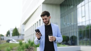 Harika sakallı iş adamı, mali bölgede iş görüşmeleri sırasında cep telefonu kullanıyor. Başarılı erkek CEO cep telefonuyla mesajlaşırken gülümsüyor.