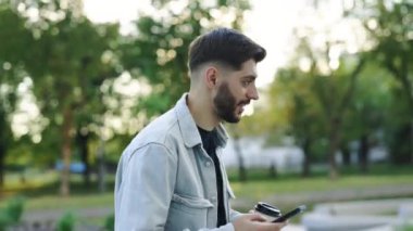 Çekici beyaz Ermeni genç sakallı adam caddede yürüyor. Telefonla gülüyor, günbatımı cep telefonu moda interneti kullanıyor. Teknoloji şehrinin dışında mutlu bir yaz tatili..