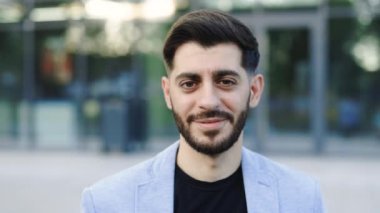 Resmi kıyafetli, gülümseyen beyaz sakallı adam sokakta kameraya bakıyor. Mutlu iş adamı portresi. Oldukça yavaş çekimde modern müdür..