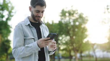 Gülümseyen sakallı iş adamı akıllı telefonu ofisin önünde tutuyor. Yönetici cep telefonu uygulamalarını kullanıyor. Dijital teknoloji uygulamaları ve kurumsal kalkınma için çözümler