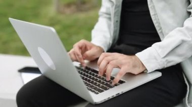 Male user hands typing on laptop keyboard sit on bench, mixed race ethnic businessman hipster student professional study work with pc software technology concept. Freelancer working on laptop.
