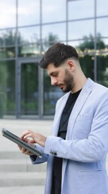 İnternette tablet bilgisayar okuyarak iş yapan genç bir adamın portre modu. Avrupa saç stili. Kurumsal insanlar. 4k UHD