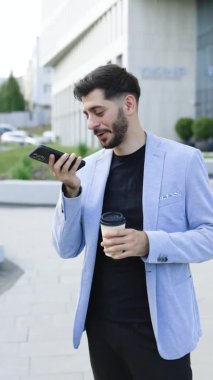 Arkadaşlarıyla hoparlörde konuşan sakallı bin yıllık iş adamının dikey videosu ses tanıma programını mobil uygulama üzerinde sanal yardımcı dijital uygulama kayıt ses mesajı ile çalıştırıyor.