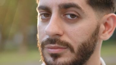 Yüzü sakallı yakışıklı bir adam kameraya bakıyor. Sokak şehri yaz adamı şehrinde çok çekici ve güzel bir erkek duruyor. Süper yavaş çekim 4k UHD