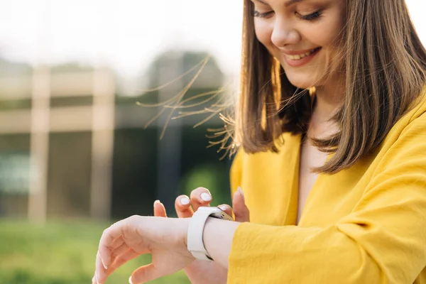 Smart watch. Smart watch on a womans hand outdoor. Appealing young elegant woman touching a smartwatch. Caucasian woman use her wearable smart watch and smiling.