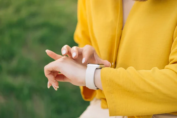 Smart watch on womans hand outdoor. Womans hand touching a smartwatch. Females hand uses of wearable smart watch at outdoor.