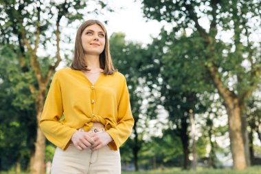 Gün batımında çekici bir kadın açık havada güzel mavi gözlerle gülümsüyor. Dışarıda dur ve rahatla. Mutlu rahatlama.