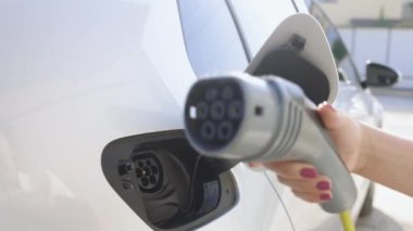 Female hands disconnect and show DC fast charging socket Europe type two. Business woman holding an electric car plug of EV. Woman plugging an electric car or EV at home electric charging station.