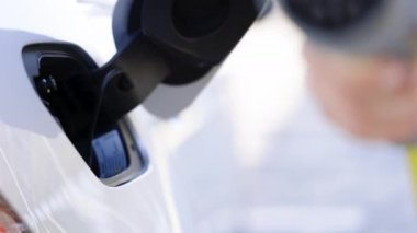 Elektrikli araç tip 2 'yi şarj ediyor. Kadın elleri elektrikli otomobilinin fişini çekiyor. Kadın eli, ereksiyon halatlı bir araba yerleştiriyor. Elektrikli eko araba şarjı.