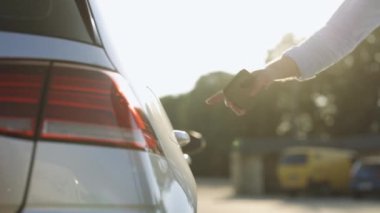 Elektrikli arabanın şarj istasyonundan fişini çeken tanınmamış bir adam. Akıllı telefondaki uygulamayı kullanarak elektrik kablosunu elektrikli arabaya takan bir erkek. İş adamı açık hava şarj istasyonunda elektrikli araba yüklüyor.