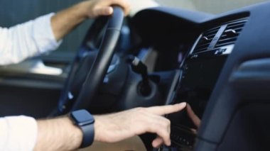 Unrecognizable man hand touching, clicking, tapping, sliding, dragging and swiping on screen monitor on modern luxury car. Interface concept.