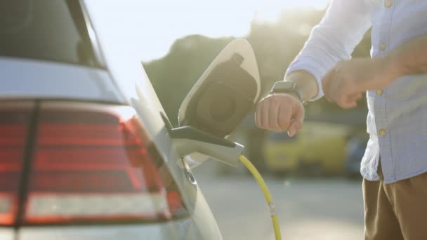 Unrecognizable Man Disconnects Charging Cable Electric Vehicle Using Smartwatch Male — Vídeos de Stock