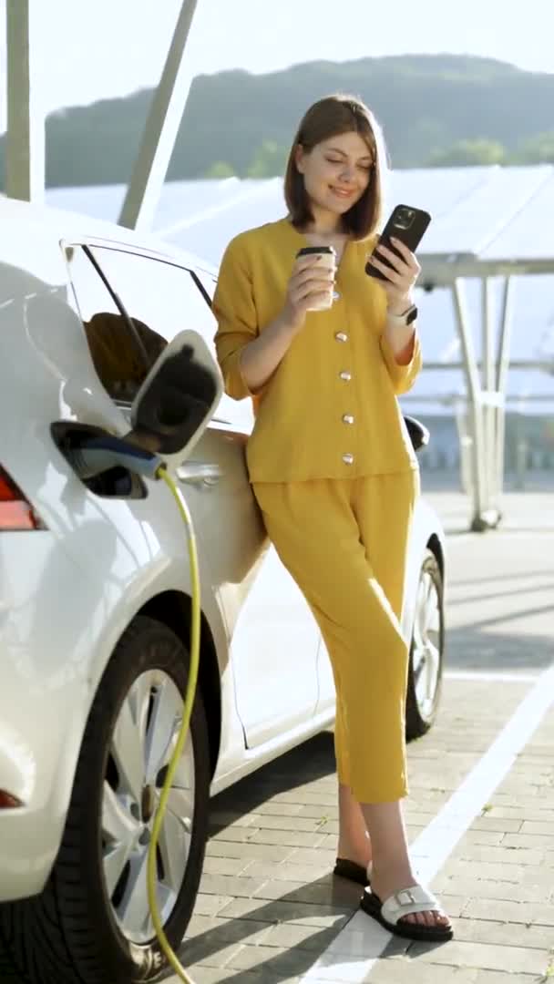 Elinde Cep Telefonu Kahve Fincanı Olan Bir Kadının Elektrikli Arabanın — Stok video