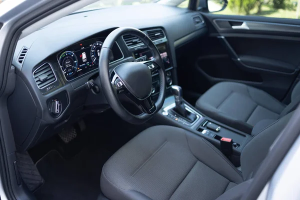 Car dashboard with a digital touchscreen. Steering wheel of a electric vehicle, interior cockpit, electric buttons, digital speedometer, front seats, textile, windows, console, gear shift.