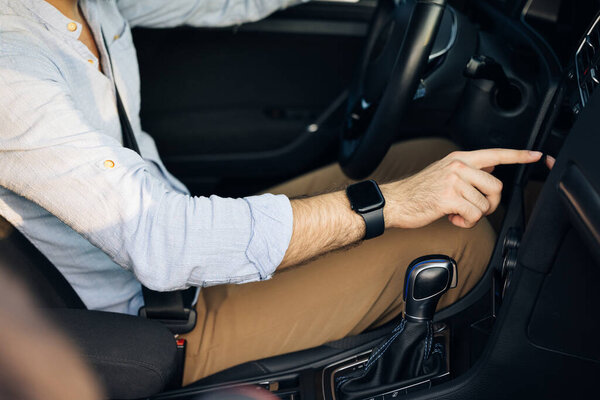 Неузнаваемый мужчина трогает, щелкает, стучит, скользит, тащит и тащит на экране монитора на современном роскошном автомобиле. Концепция интерфейса.