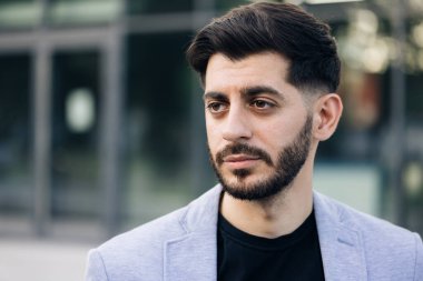 Sakallı, yakışıklı, beyaz iş adamının portresi iş merkezinin yakınındaki kameraya ciddi ciddi bakıyor. Başarılı kariyer çekici müdür yakışıklı kendine güvenen.