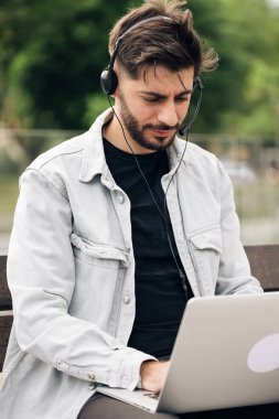 Adam kulaklık takıyor ve bilgisayar başında öğretmeniyle konuşuyor. Bilgisayar kameralı sohbet kullanarak öğrenen erkek öğrenci notlar alır. Uzaklık eğitimi kavramı