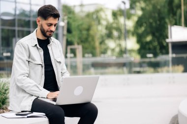 Ofisin yakınında dizüstü bilgisayarla çalışan mutlu Ermeni iş adamı. Beyaz bir erkek yönetici bilgisayarlı uzaktan eğitim kullanıyor, internette geziniyor, sanal toplantı yapıyor, bilgisayarda yazıyor..