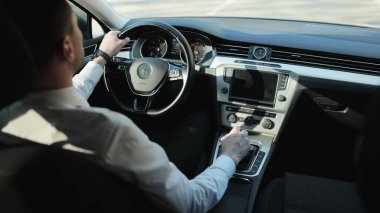 Beyaz tişörtlü beyaz sakallı yetişkin bir adam güneşli bir günde otobanın karşısında lüks bir araba kullanıyor. Yan bakış açısı. Başarılı iş adamları seyahat yaşam tarzı. Seyrüsefer. Otoyol ulaşımı.