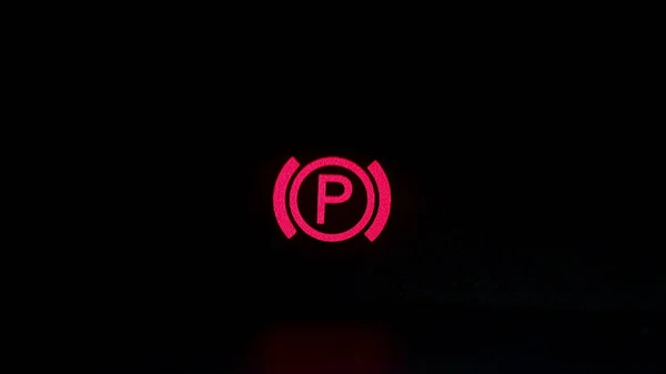 Parking brake control light in car dashboard. Close up of cars parking brake light coming on, on the dashboard.