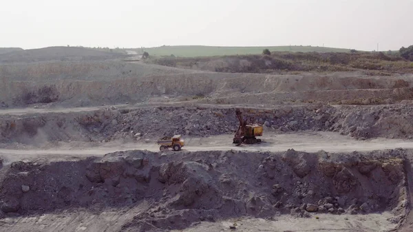 Electric Truck loaded with ore is riding along the mine site. Industrial quarry, heavy industrial machinery working at the mining open pit.